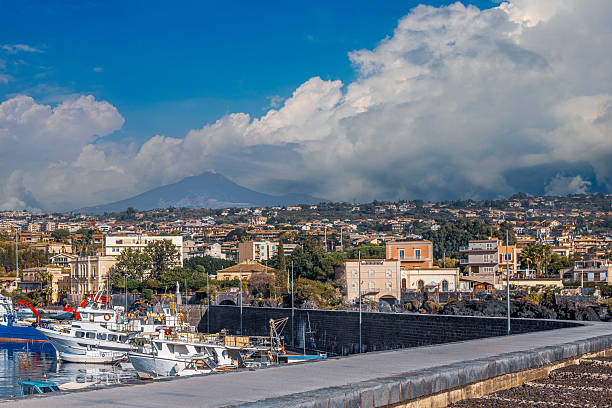 Catania, Italy - November 1, 2024: Dirty Catania beach with a huge overhanging Etna volcano, a sunny day and a black huge dangerous mountain, Sicily, Italy, editorial image