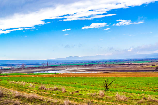 East Balkan Mountains valley spring scenery Bulgaria. plowed field in the foregrond and Balkan Mountains in the backgrond and summer blue sky seen from train moving on Karnobat-Varna railway track.