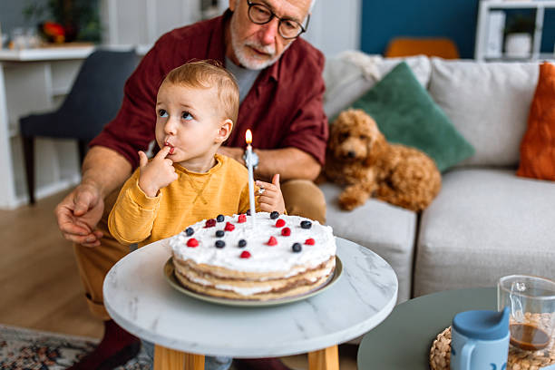 istock Grandson and senior granfather blowing birthday candle. 2241819237