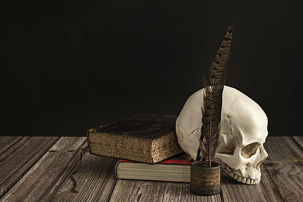 Close-Up Of Human Skull With Cross On Book At Table