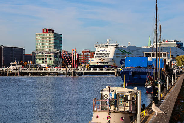 Kiel, Germany - 17. October 2025: Ships docked in the harbor with a modern building and clear blue sky