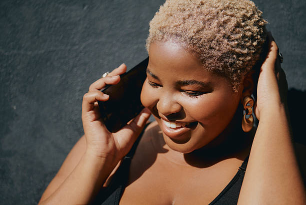 istock Confident young black woman smiling outdoors while on a phone call using a smart phone against textured wall 2241825889