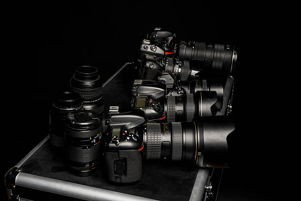 A few cameras and lenses on a black travel suitcase