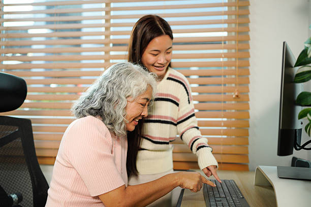 istock granddaughter teaches her grandmother work with computer at home 2241830997