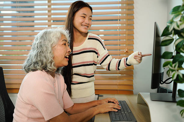 istock granddaughter teaches her grandmother work with computer at home 2241831001