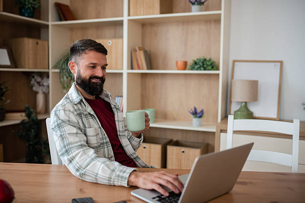 istock Casual man smiling at laptop with beverage 2241834539