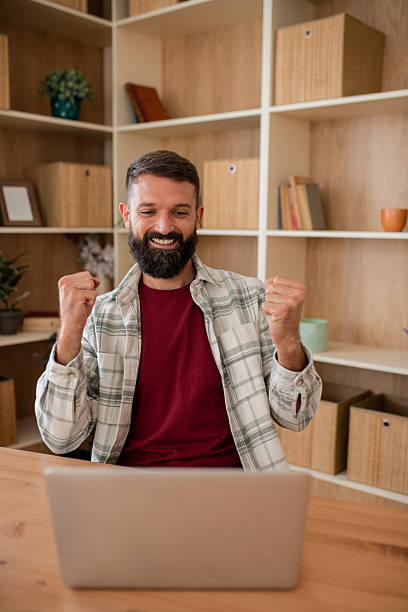 istock Man celebrating at home desk 2241834635