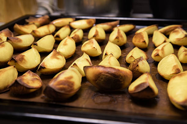 Roasted potatoes, perfectly golden and slightly crispy, cover a baking tray, making an appetizing side dish ready to complement any meal during dinner time.