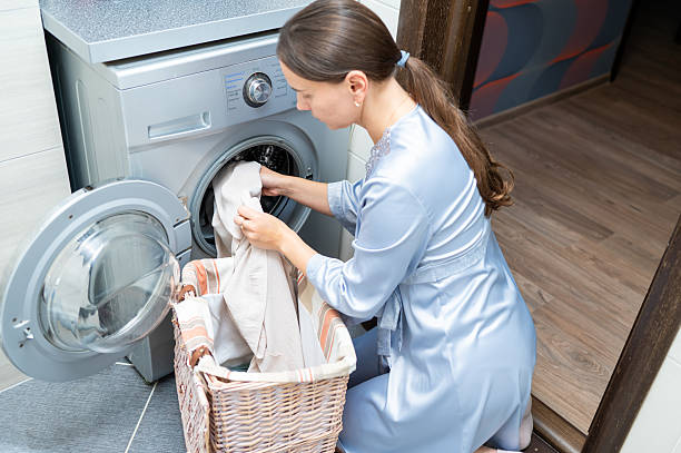 istock Housewife loading dirty laundry into washing machine at home 2241836628