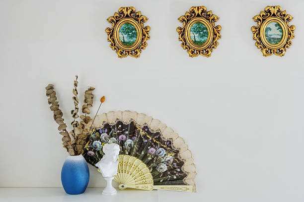 istock Wooden shelf with decorative objects with gilded wood frames, vases with dried plants and a patterned fan 2241839470