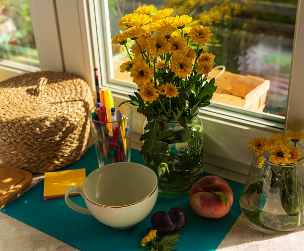 istock Still life with yellow chrysanthemums and fruit on windowsill 2241839962