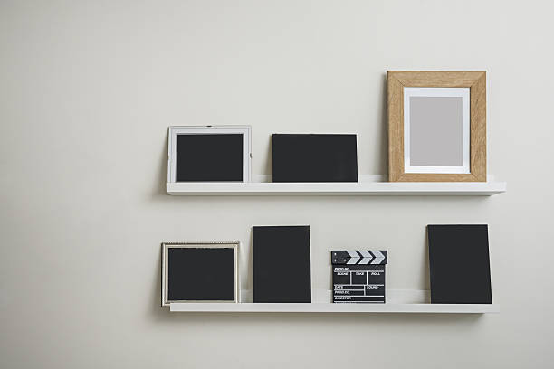 istock white wooden shelves with several black frames a movie clapperboard leaning on it 2241848299