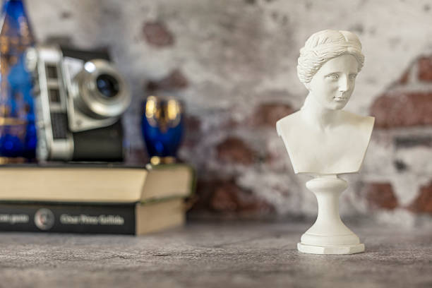 istock Small bust of classical Greek figure on gray background with half bare bricks on the wall and other blurred decorative objects 2241849006