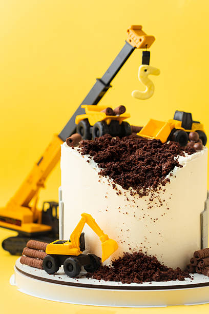 istock Birthday cake for five year old kid, decorated with construction vehicles. Heavy car themed homemade cake for toddler boy birthday celebration with toy excavators and crane on the yellow background. 2241854682