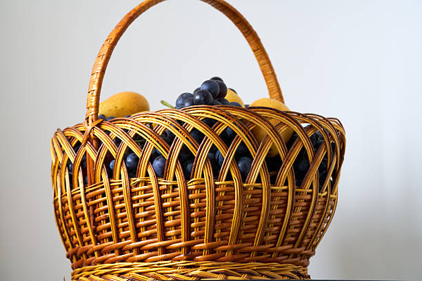 Wicker basket with grapes and pears on a white background