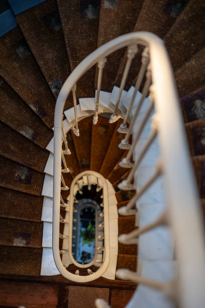 istock Looking down an elegant vintage spiral staircase. The white handrail creates a leading line, drawing the eye into the depths. A concept of architectural detail and perspective. 2241871263