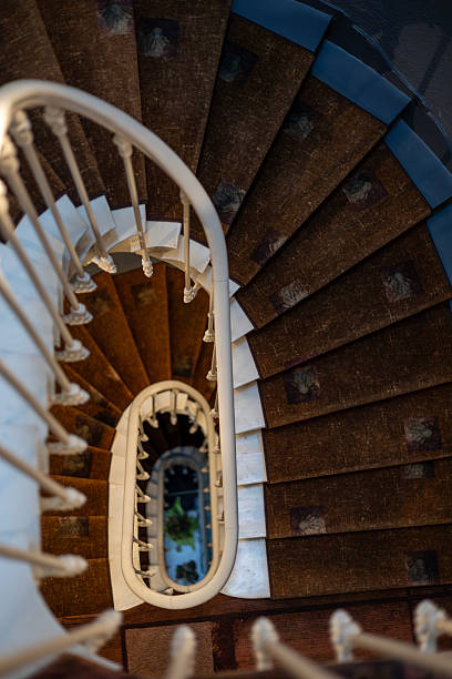 istock Looking down an elegant vintage spiral staircase. The white handrail creates a leading line, drawing the eye into the depths. A concept of architectural detail and perspective. 2241871266