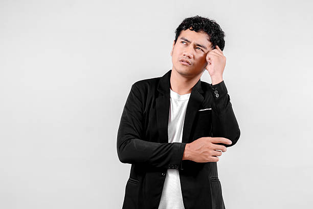 istock Indonesian man in black blazer thinking seriously with puzzled expression on white background 2241876182