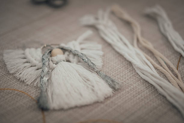 istock See a close-up of a handcrafted macrame angel on neutral fabric, emphasizing its soft texture and delicate design. This creative DIY craft piece showcases intricate artistry, perfect for those 2241876360