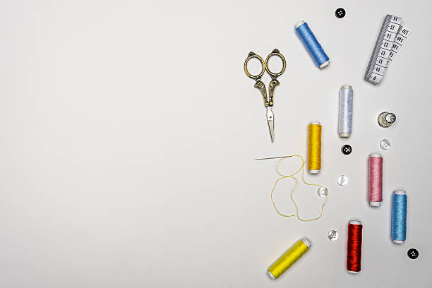 A collection of sewing tools and supplies in a sewing kit, isolated on a white background. Items include color threads, buttons, needle, tape measure, scissors, and seam ripper, equipment and work tools needed for a typical fabric sewing project.