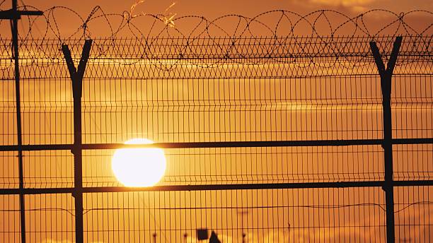 istock Airport security fence at sunset, barrier silhouette with razor wire 2241880483