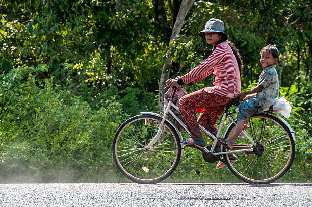 Chong Khneas, Tonle Sap Lake, Cambodia - oct 27, 2015 :  on the road near the Angkor Wat site, a mother returns home on a bicycle with her child