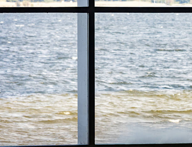 View out of windows at a building beside the sea showing supporting cross structure.  Waves and background shore.