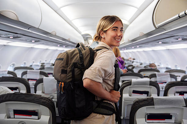 istock Smiling Female Traveler With Backpack Standing in Airplane Cabin Ready for Takeoff 2241896129