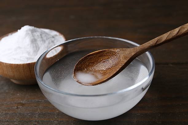 istock Adding baking soda into bowl of water at wooden table, closeup 2241898938