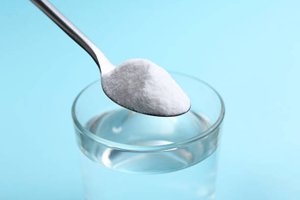 istock Adding baking soda to glass of water on light blue background, closeup 2241899036