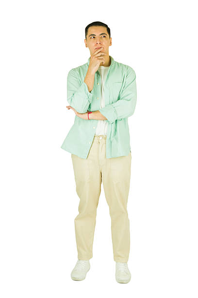 Full length young man lost in thought, contemplating an idea or decision, standing on a white background