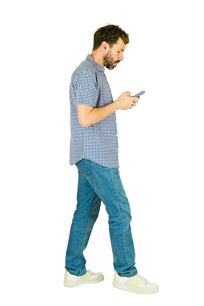 istock Profiel view of a man walking and texting on mobile phone 2241902847