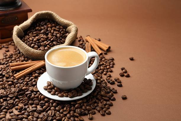 istock Cup of hot coffee, beans and cinnamon on brown background, space for text 2241903860