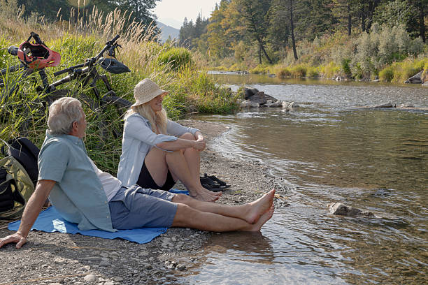 istock Mature couple with e-bicycles relax on riverbank together 2241926218