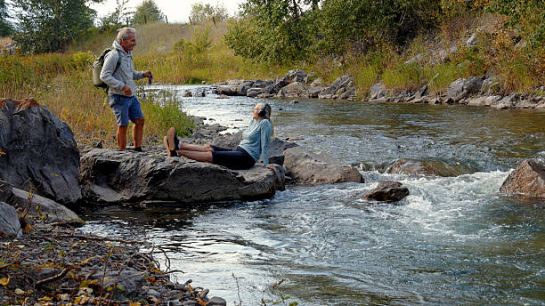 istock Mature couple relax on riverbank together 2241926249