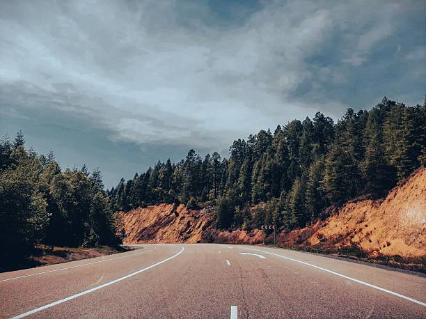 A view from a car on a country road, surrounded by forests and mountain cliffs on either side. Cinematic effect.
