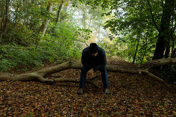 sad man in dark forest early morning feeling alone, man looking down feeling sad and worried, man with feelings in dark nature image, feeling concept image