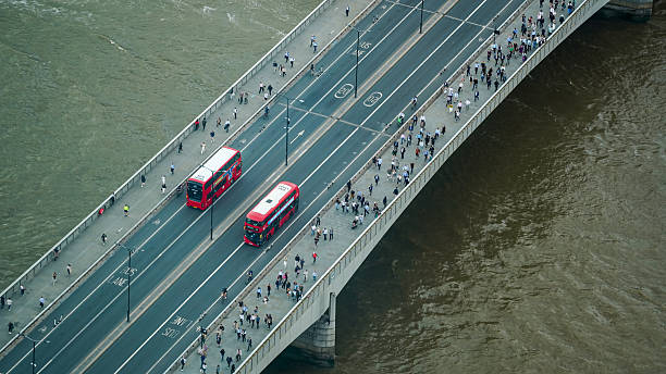 Asian Tourists Walking in London on a Bridge While Being Passed by a Double Decker Bus