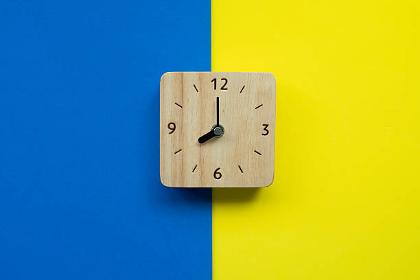 istock Retro alarm clock on blue and yellow table background, vintage s 2241955646