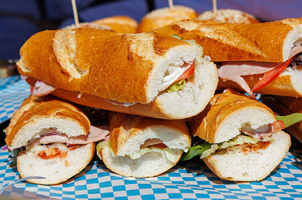 A stack of sandwiches with a variety of fillings. Some of the sandwiches are open and some are closed