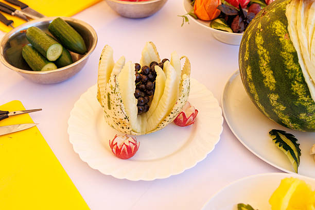A plate of fruit with a watermelon on top. There are also other fruits on the table