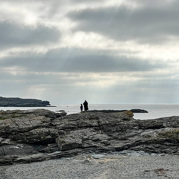 View across the beach at Trearddur Bay, Anglesey, North Wales, UK.  People can be seen stood on the rocks