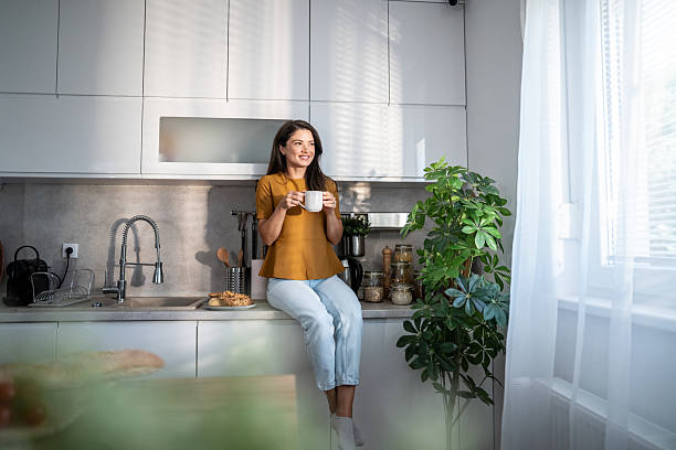 istock Woman enjoying morning coffee in sunlit kitchen 2241975592