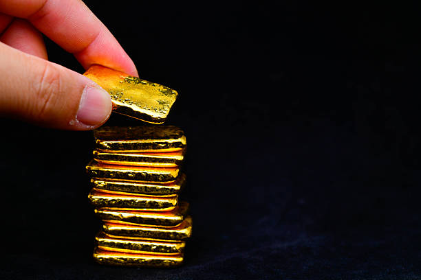 istock Hand holding a gold bars on black background 2241976358