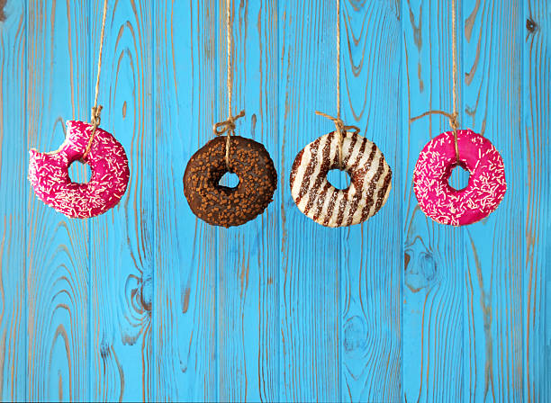 Four Donuts Hanging on Strings on Blue Wooden Background