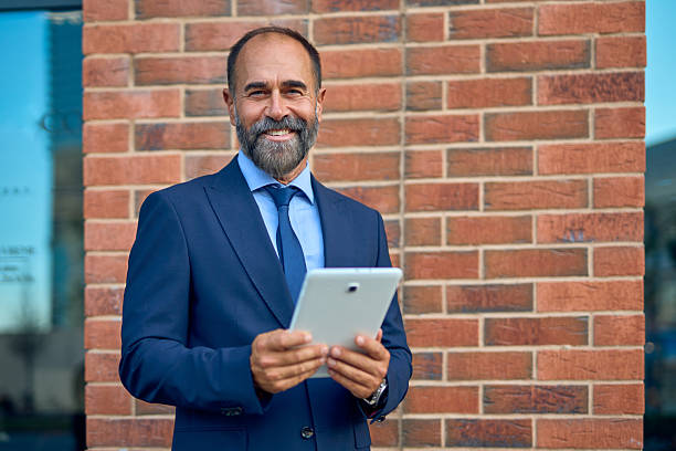 istock Professional mature businessman smiling and holding a tablet 2241979333