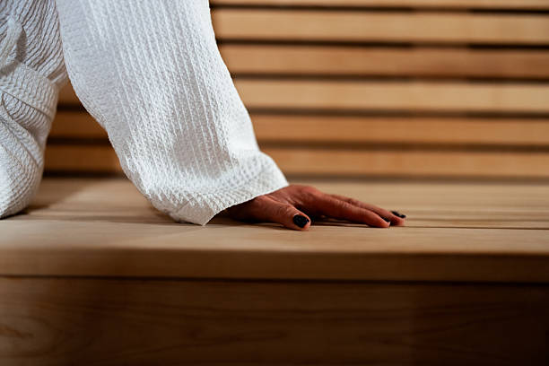 Woman in white bathrobe relaxing and enjoying warmth inside a traditional wooden sauna