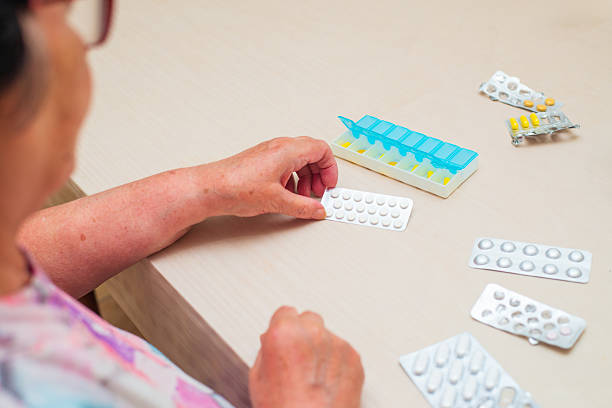 istock Senior woman putting pills into the plastic pill organizer 2241981416