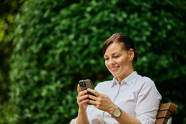Smiling Woman Using Smartphone Outdoors on a Sunny Day in the Park