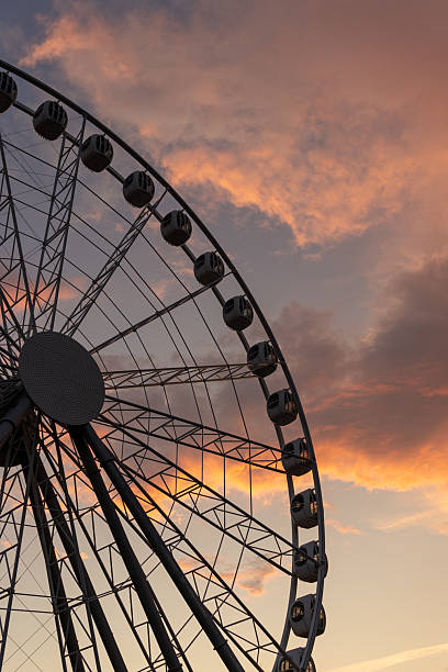 istock large Ferris wheel against a cloudy sky. The Ferris wheel is surrounded by sunset clouds. 2241982862